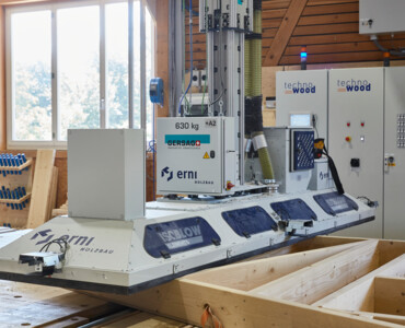 Automatisiertes Einblasen der Holzbauelemente mit dem Karin-Stapelkran und der Dämmplatte.